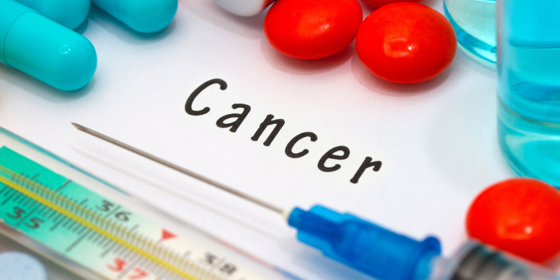 The word cancer in the center surrounded by tools and medications.