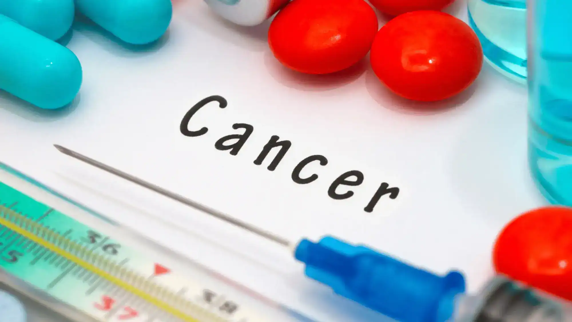 The word cancer in the center surrounded by tools and medications.