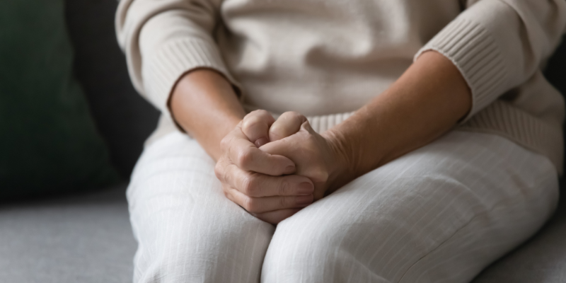 A woman folding her hands over her lap.