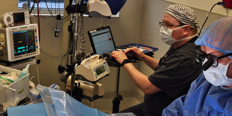 An anesthesia technician monitoring machines during a pet's surgery.