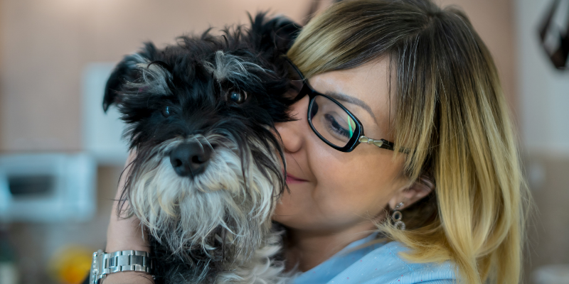 A close-up image of a woman snuggling her dog. 