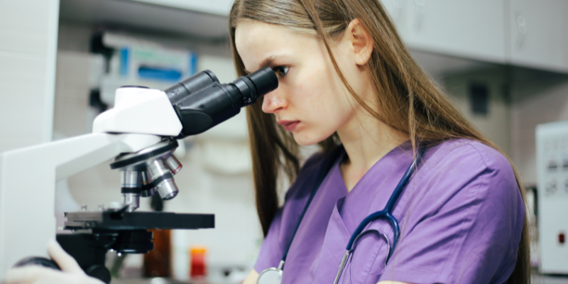 A veterinary technician looking into a microscope.