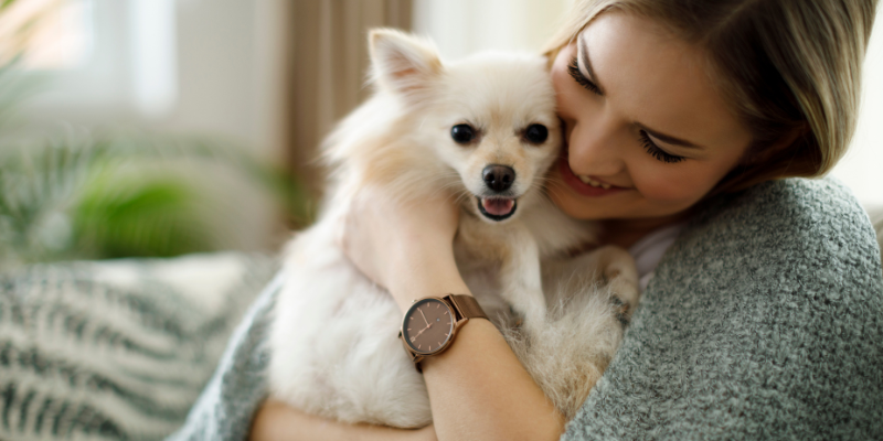 A woman closely hugging her small dog.