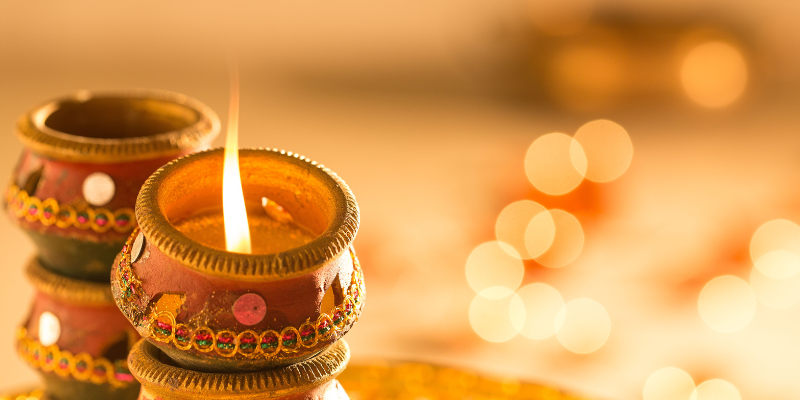 Lit diyas surrounded by gold lights. 