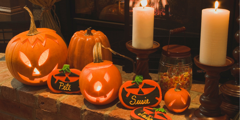 A table with Halloween decorations including Jack-O-Lanterns, candles, and fabric pumpkins.