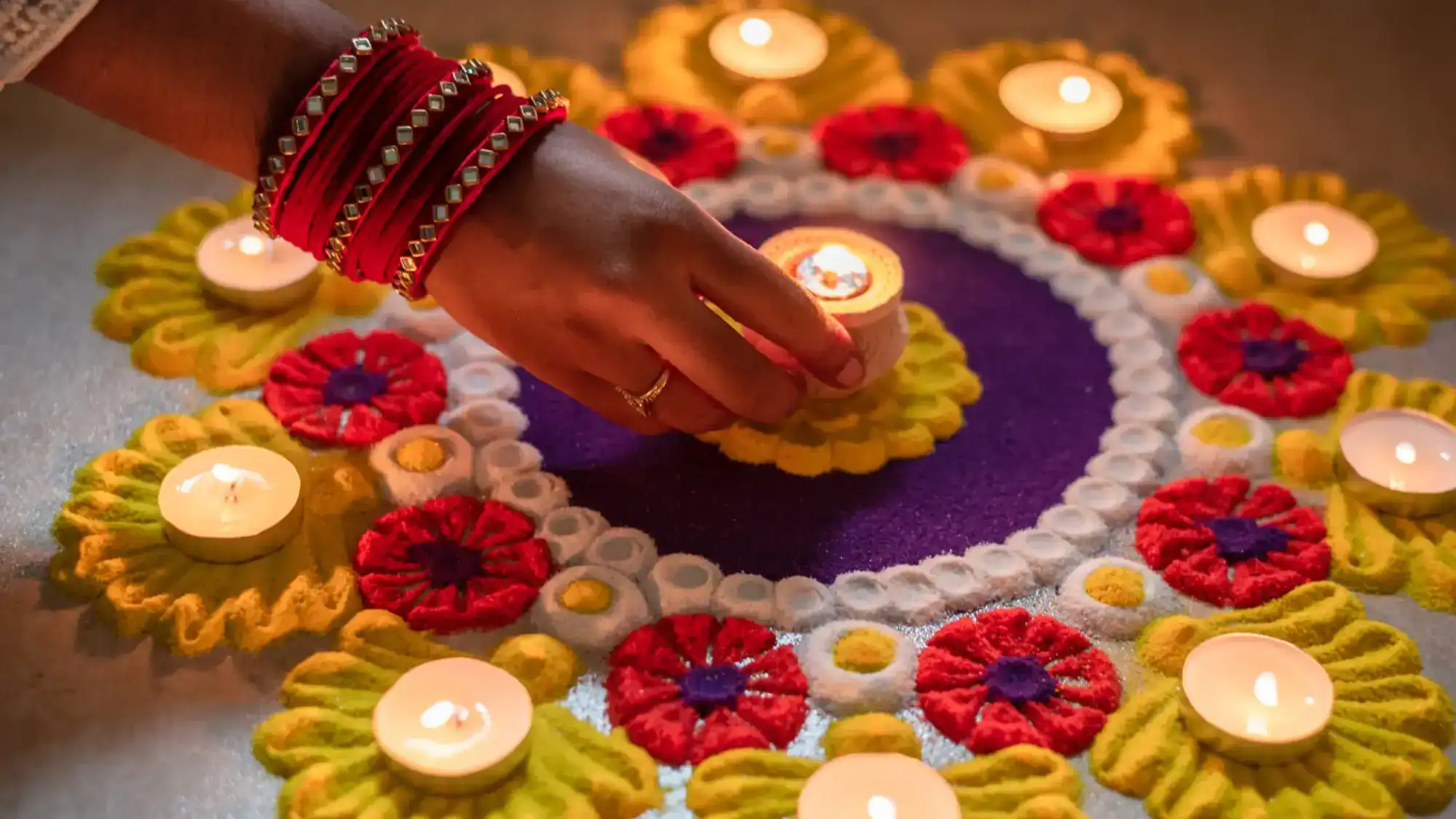 A colorful rangoli display with candles.