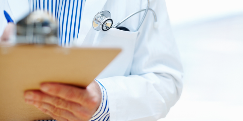 A veterinarian in a white coat holding a clipboard.
