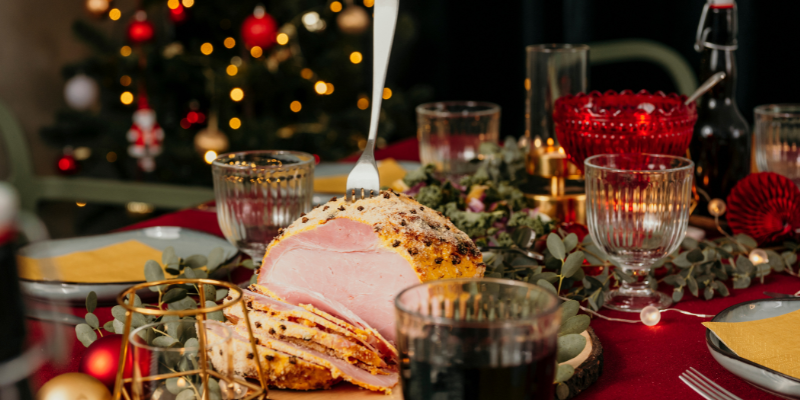 A table with a Christmas fest, including a large holiday ham centerpiece. 