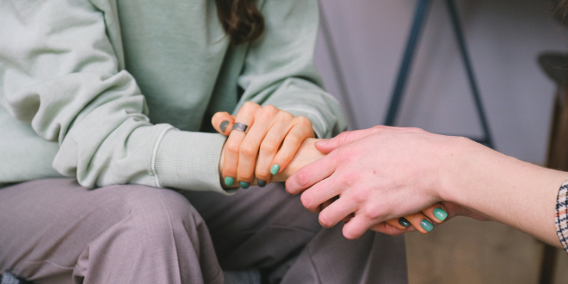 Two people holding hands, offering comfort.