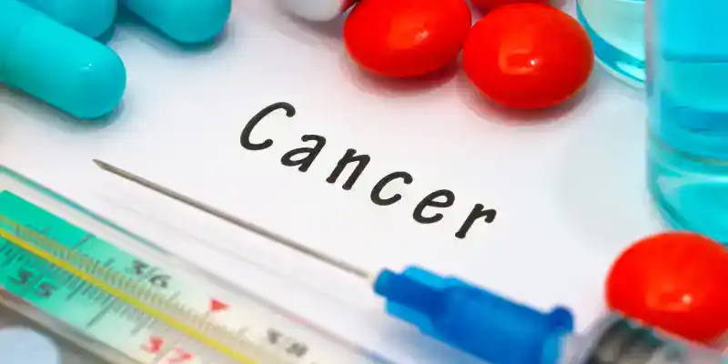 The word cancer in the center surrounded by tools and medications.