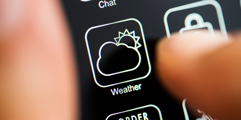 A close-up of someone selecting a "weather app" on their phone screen.