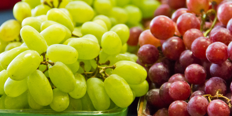 A bowl full of green and red grapes.